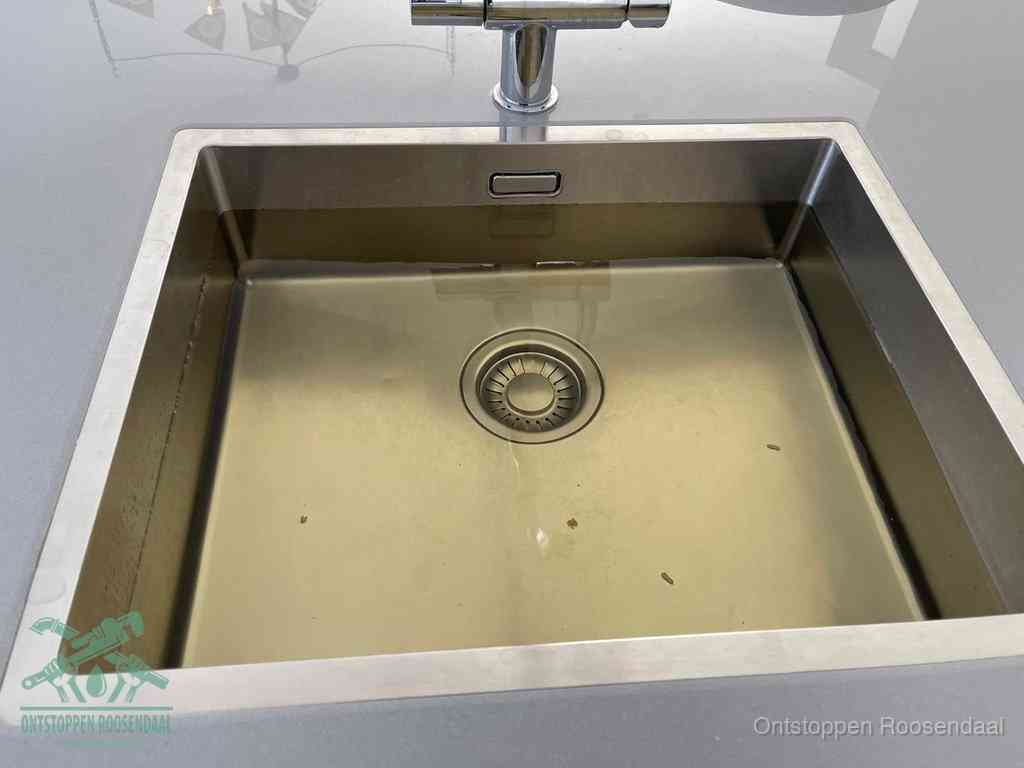 Stilstaand water in een rvs spoelbak dat niet wegloopt, een duidelijk signaal van een gootsteenverstopping in Roosendaal