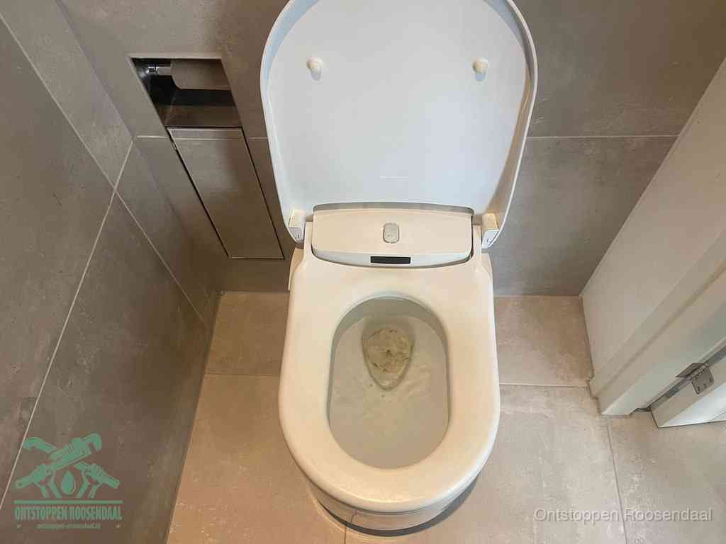 Een wit hangtoilet waarin een prop wc-papier op het water blijft drijven, een duidelijk signaal van een verstopte wc in Roosendaal