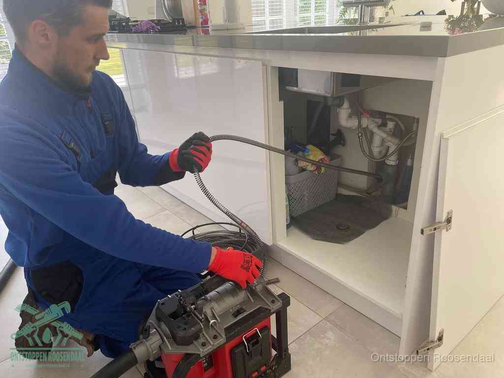 Een monteur reinigt de keukenafvoer grondig met een veermachine om terugkerende gootsteenverstoppingen te voorkomen in Roosendaal