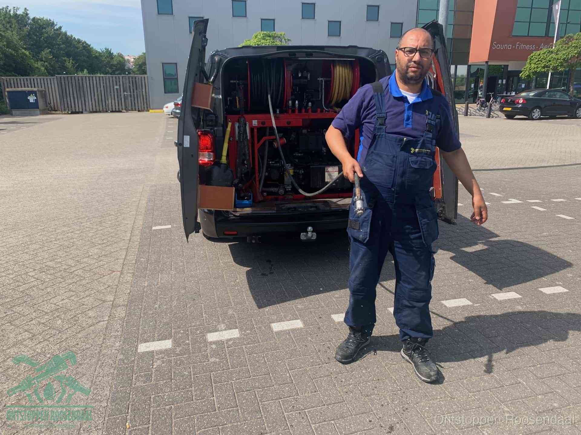 Een monteur bij zijn bestelbus met een hogedruk- en rioolreinigingsunit, klaar om de oorzaak van terugkerende wc-verstoppingen aan te pakken in Roosendaal