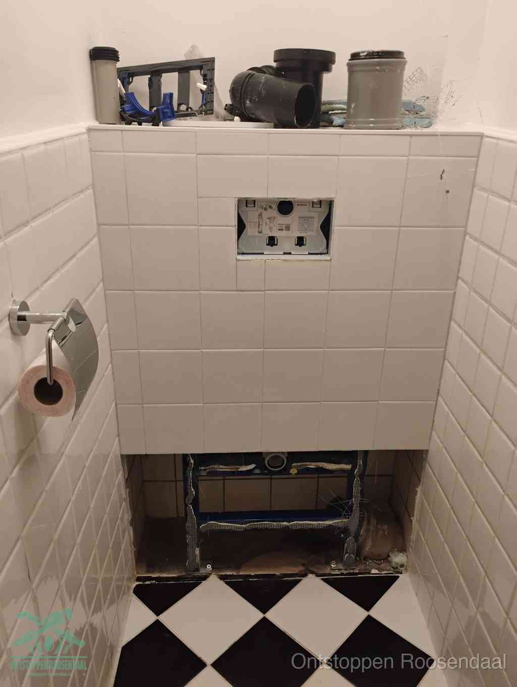 Een toiletruimte waar het hangtoilet en de inbouwreservoir-onderdelen zijn vrijgelegd voor onderhoud, periodiek nazicht voorkomt een wc-verstopping in Roosendaal