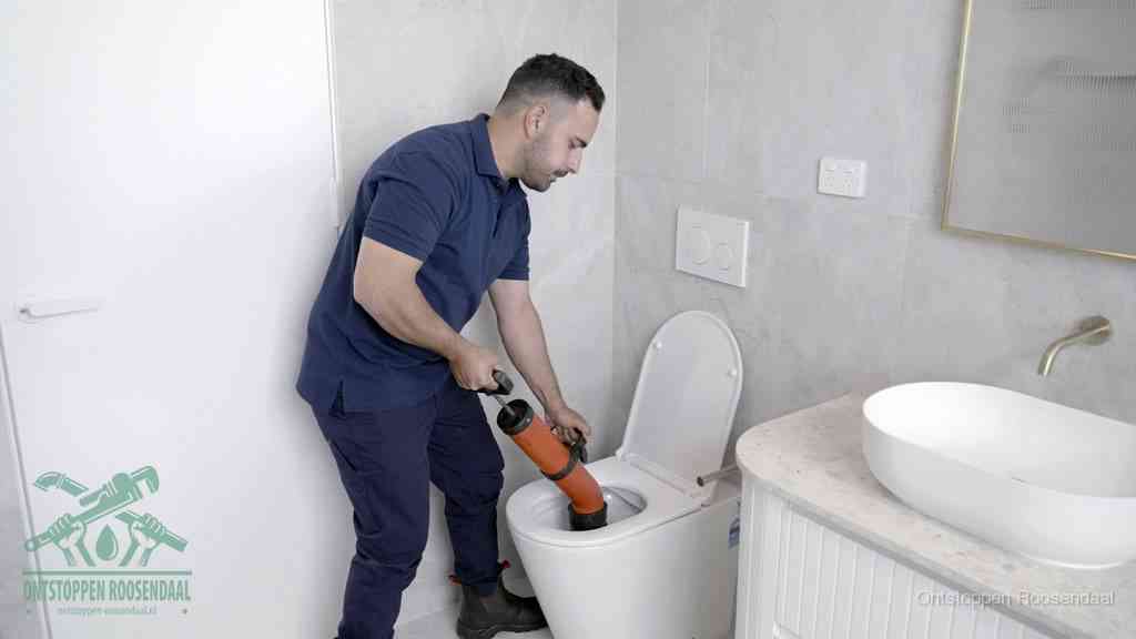 Een monteur gebruikt een handmatige perspomp (toiletontstopper) op een wandcloset tijdens het professioneel wc ontstoppen in Roosendaal
