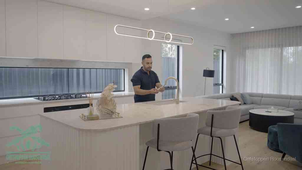 Een bewoner bij de keukenspoelbak die zelf aan de slag gaat met een verstopte gootsteen in Roosendaal
